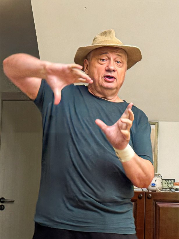 Pavel Alimov wearing a hat and gesturing with both hands.